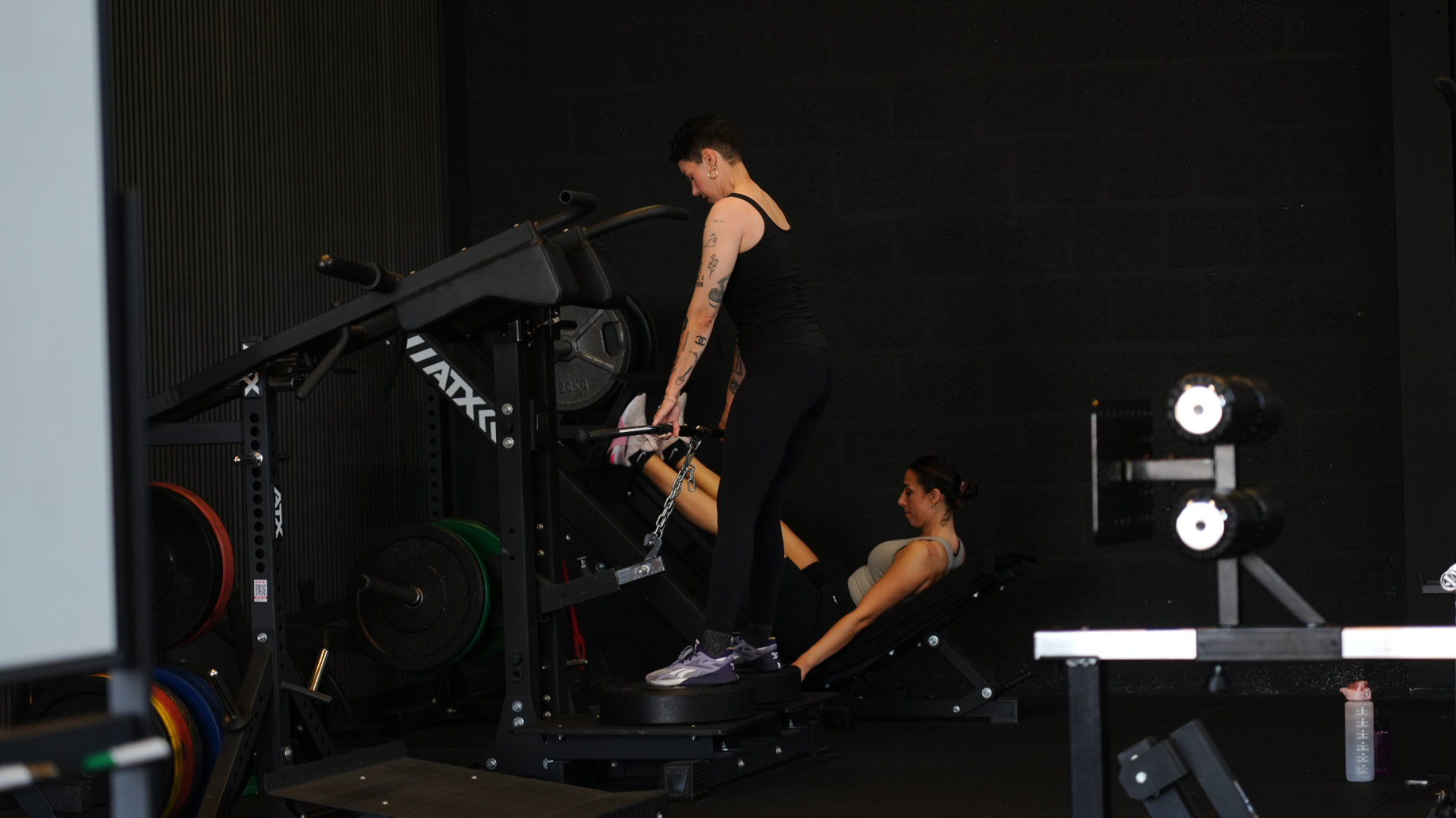 Twee leden trainen zelfstandig op de krachttoestellen in de gym