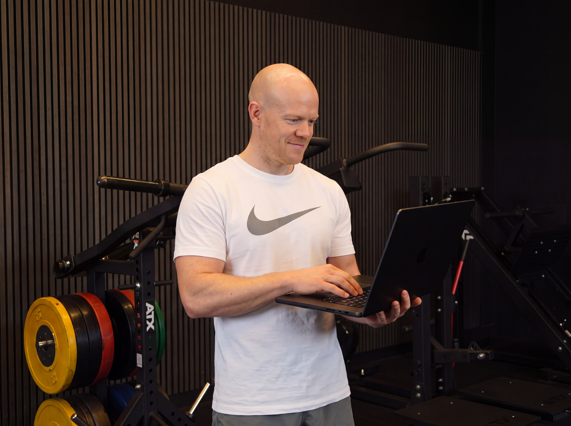 Coach Eric werkt aan een voedingsplan op zijn laptop in de gym